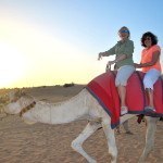 Two women riding a camel in the desert outside Dubai