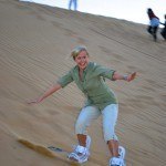 Blonde woman sand surfing on a dune in the desert